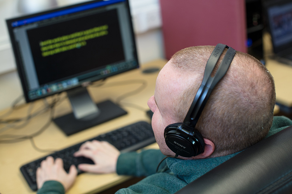 Image of man wearing headphones at a computer