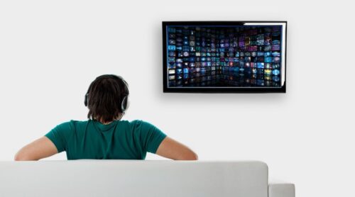 A man watching TV with his headphones
