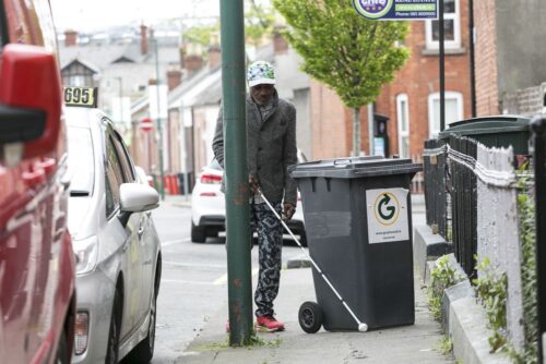 Photo of a man using his long and a bin cane is blocking his way