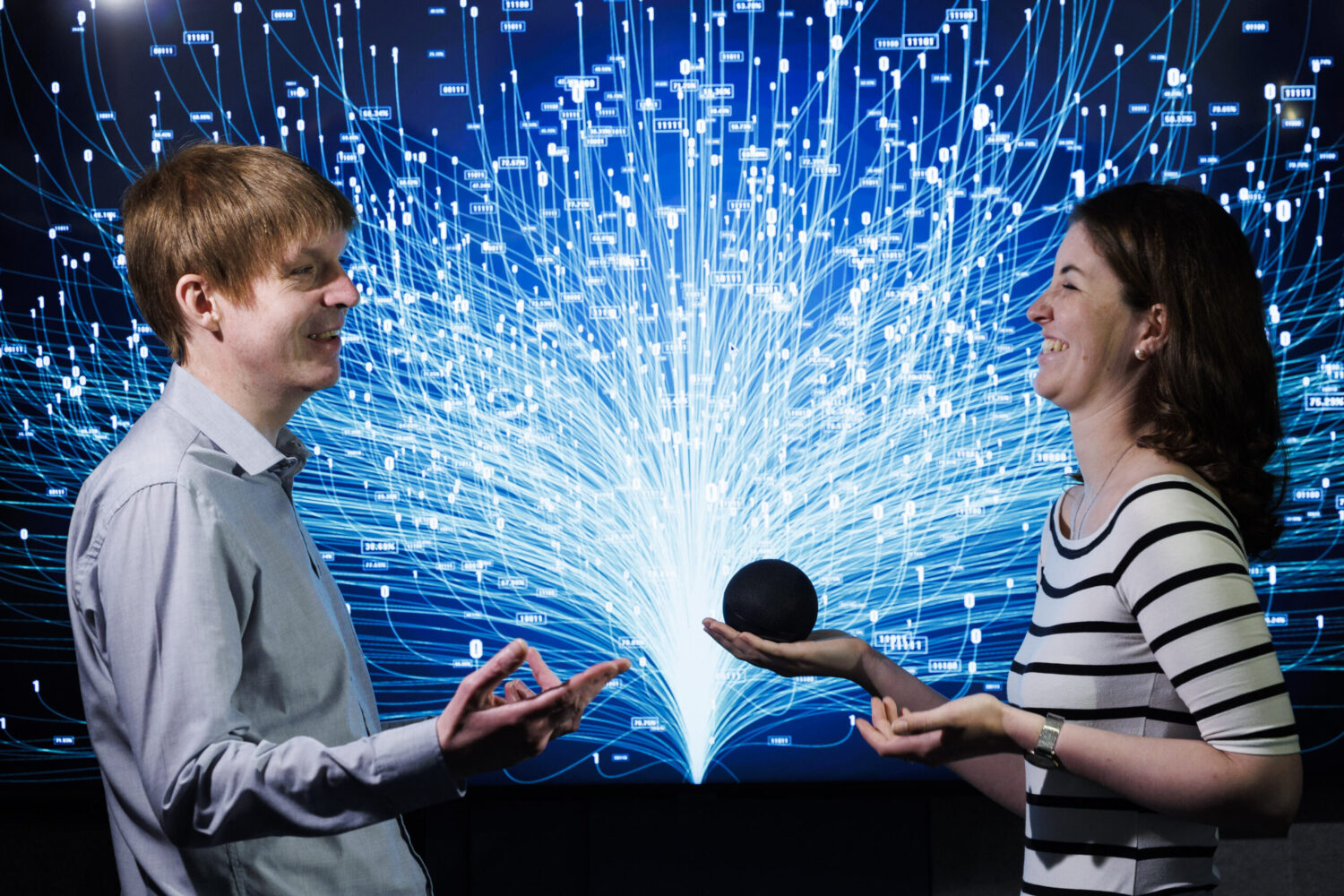 Vision Ireland service users ex Rose of Tralee Aine Sullivan and comedian Robbie Ford standing face to face and laughing in front of a black and glowing blue background at the launch of myVision Ireland Smart Hub