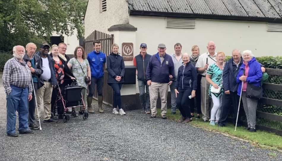 The Seen-Unseen group are standing together facing the camera and posing for a group picture at the Curragh Beag and Racing Stables.