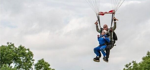 A woman and a man harnessed together as they come in to land following a sky dive