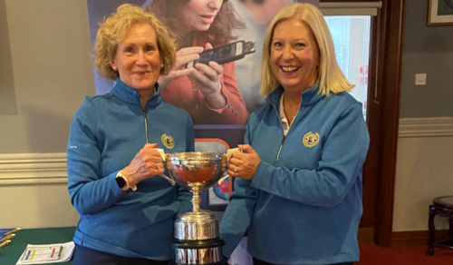 Mary Bell and Catherine Monaghan who bagged the big prize in the ladies’ event, the Granard Cup are standing together, wearing matching light blie jackets, and are holding their trophy in front of an Vision Ireland banner.