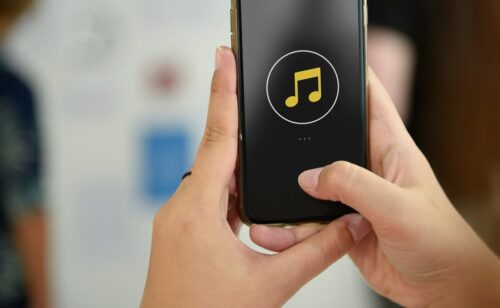 Hands holding a smartphone with a music note displayed on the screen