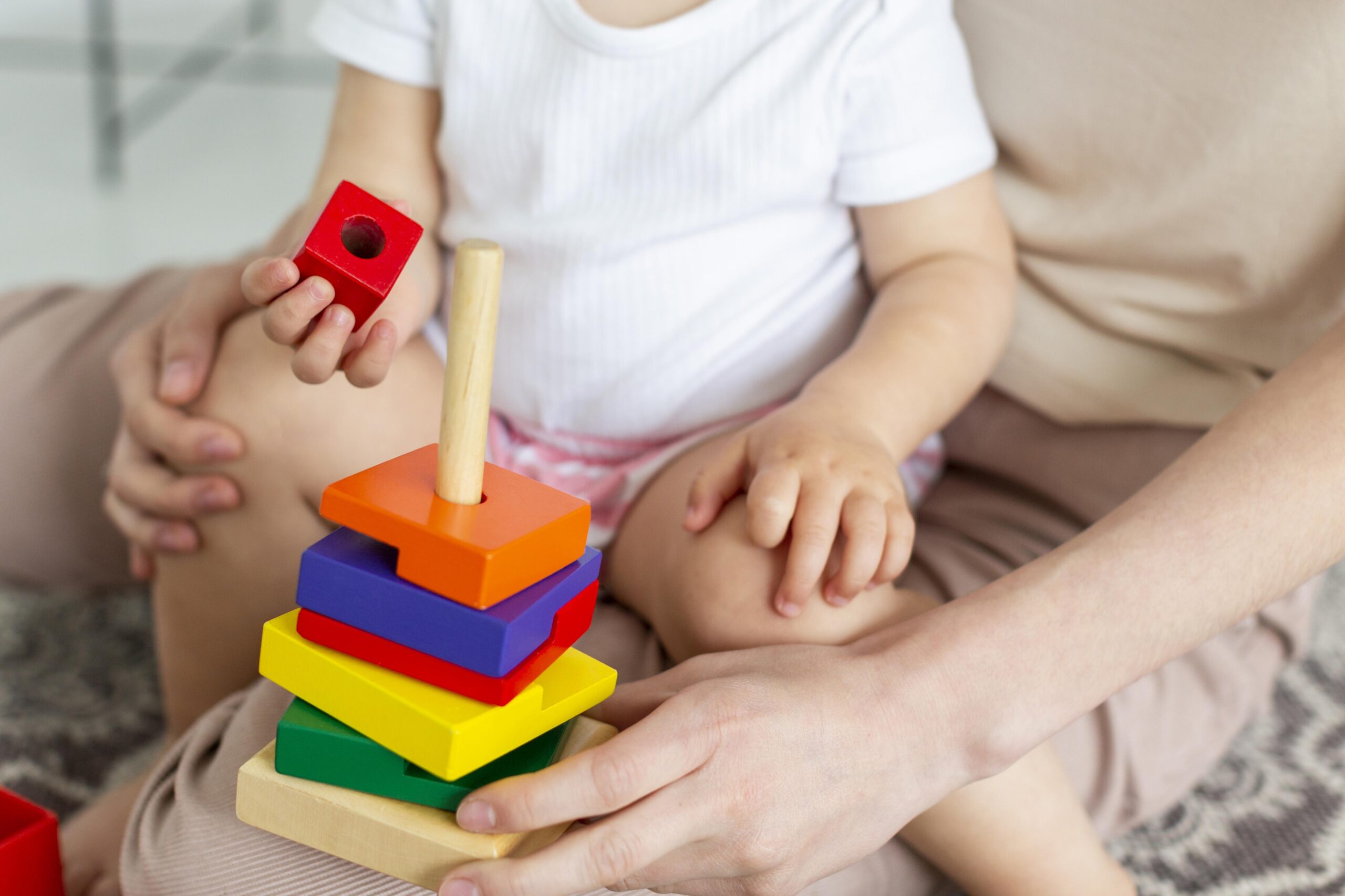 image of a toddler playing while sitting on a woman's lap
