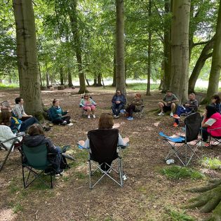 A group of participants sit around a circle in the woods