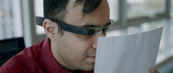 Man using Envision glasses to read a printed document