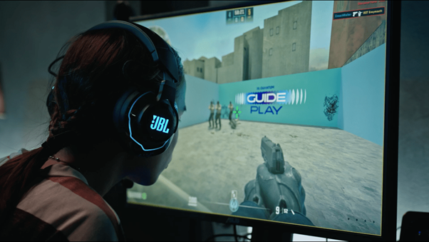 Man wearing JBL headphones playing shooting game on computer